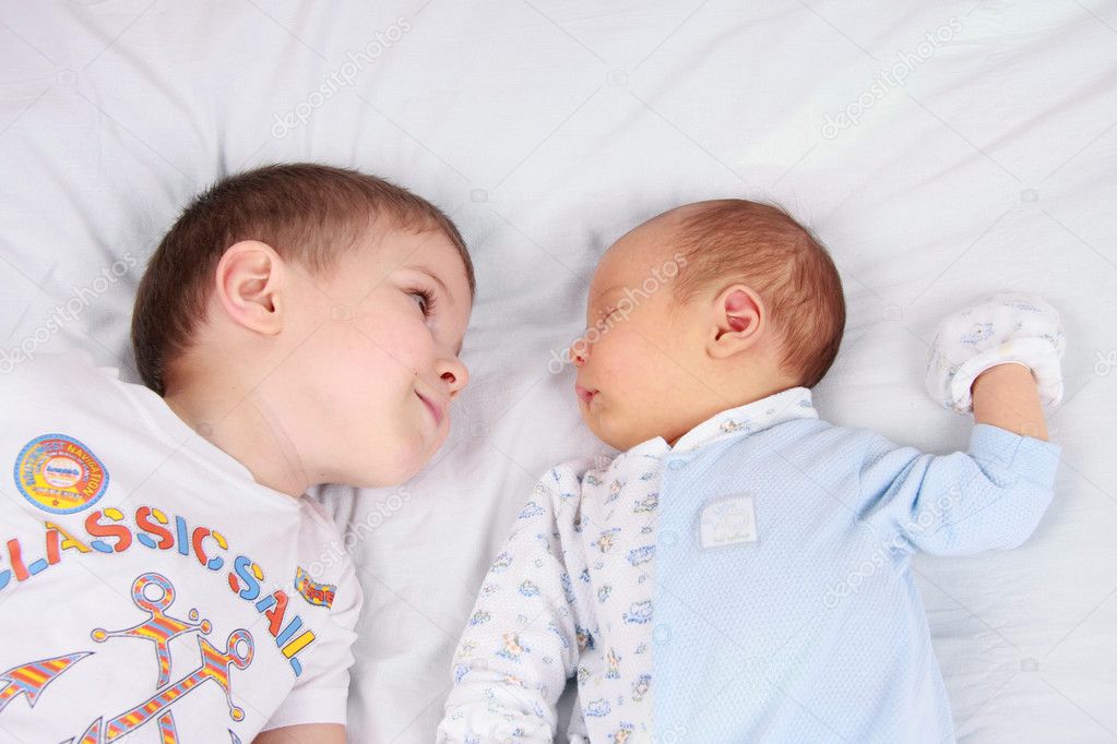 Two baby boys twin brothers lying on a bed