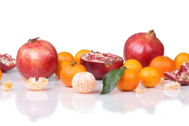 Group tangerines and pomegranate on the reflective surface isola