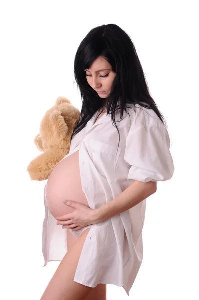 白で隔離される熊のぬいぐるみでかなり黒髪の妊娠中の女性 — ストック写真