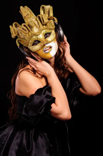 性感的女人在金半面具听听音乐 孤立在黑色 — 图库照片