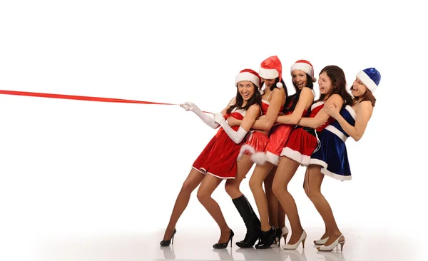 Девушки тянут красную ленточку в рождественских костюмах — стоковое фото