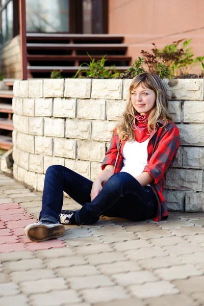 Adolescente em saia vermelha sentado na calçada — Fotografia de Stock