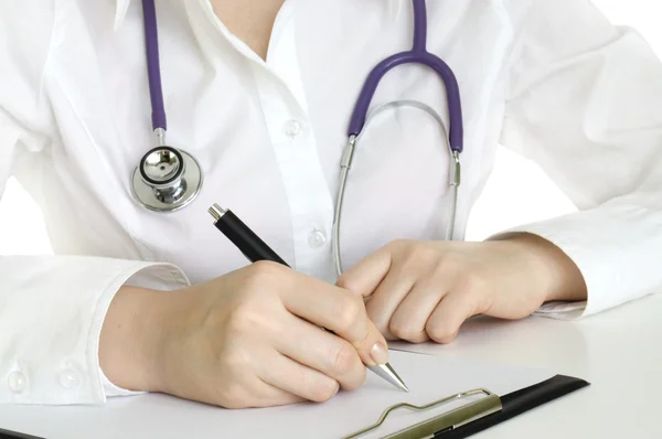 Arts met een stethoscoop schrijven op het papier — Stockfoto