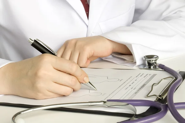 Läkare med stetoskop skriva på papper — Stockfoto