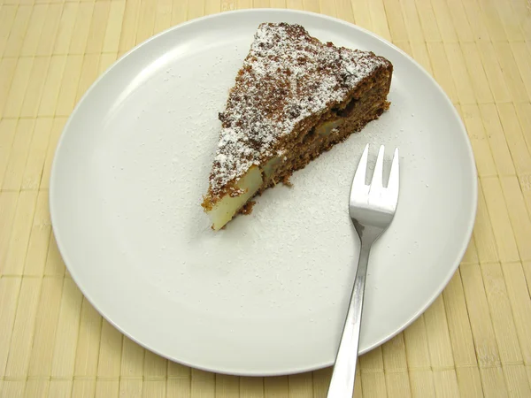 Eine Scheibe Birnenkuchen auf einem mit Puderzucker bestäubten weißen Teller — Stockfoto