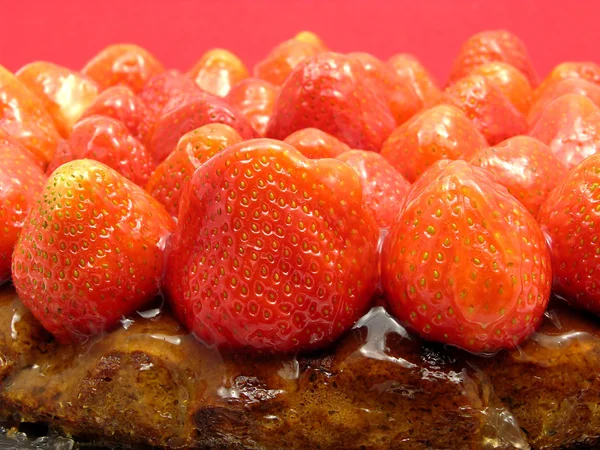 Lateral close-up view of a strawberry cake on red background — Stock Photo, Image