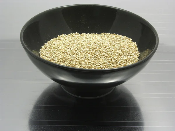 Bowl of chinaware with quinoa on reflecting matting — Stock Photo, Image