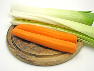 Yeşil pırasa ve turuncu bir carrot ahşap plaka