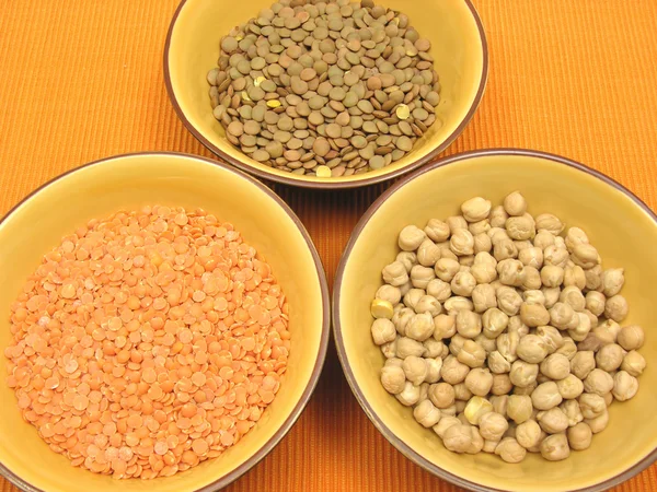 Três taças de cerâmica com lentilhas garbanzos e lentilhas vermelhas — Fotografia de Stock