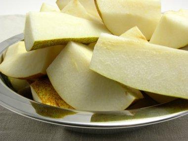 Quatered pears in a metalplate on a placemat clipart