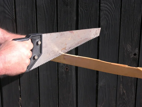Вырезание вручную и пилой перед деревянной стеной — стоковое фото