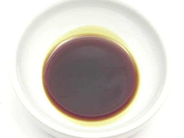 Una ciotola di chinaware con olio di semi di zucca su bianco — Foto Stock