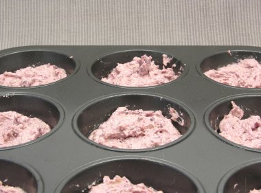 Raspberry muffins in a muffin cake pan before baking clipart