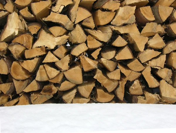 Uma pilha de troncos com neve em primeiro plano — Fotografia de Stock