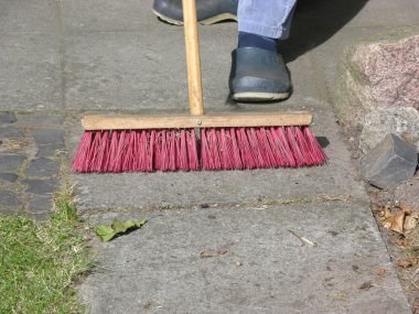 Cutout man with street brush sweeping flag stones clipart