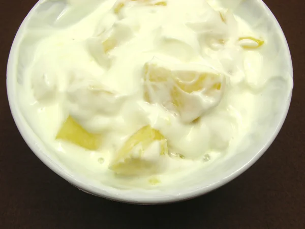 Des morceaux d'ananas dans du yaourt et un bol blanc de chinaware — Photo