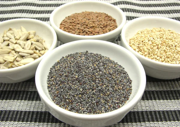 Quatro tigela com sementes diferentes em um fundo listrado — Fotografia de Stock
