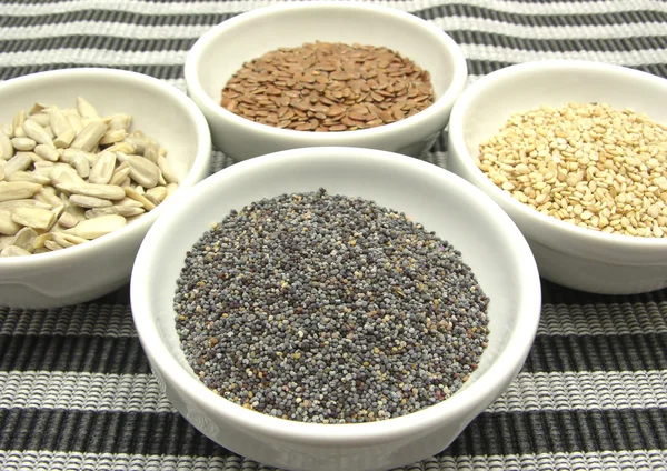 stock image Four bowl with different seeds on a striped background