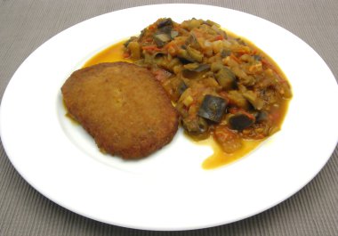 ekmekli soya peyniri göğsü beyaz bir tabak kızarmış sebze ile