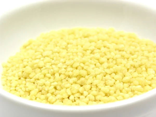 Yellow couscous in a white bowl of chinaware — Stock Photo, Image