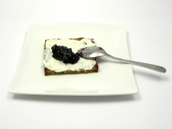 Wholemeal bread with cream cheese and bilberry jam on a plate wi — Stock Photo, Image