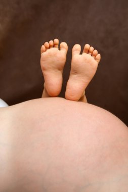 Child feet on mothers stomach clipart