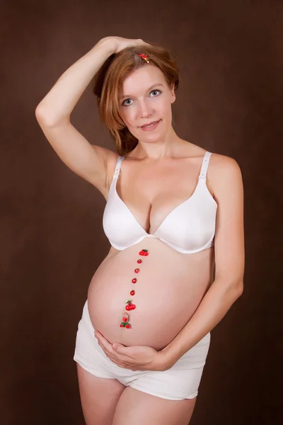 若い妊婦の腹部に面白いをモチーフにした白い下着で — ストック写真