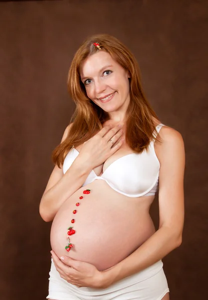 Zwangere jonge vrouw in witte kledingassortiment — Stockfoto