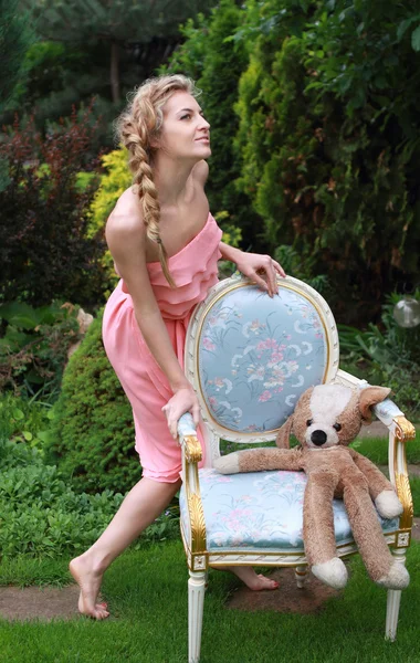 Attractive blond girl in the pink dress in the garden — Stock Photo, Image