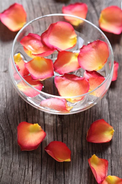 Glass bowl with water and flower petals — Stock Photo, Image