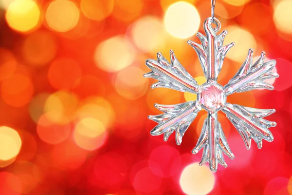 Glass snowflake against red blurred background — Stock Photo, Image