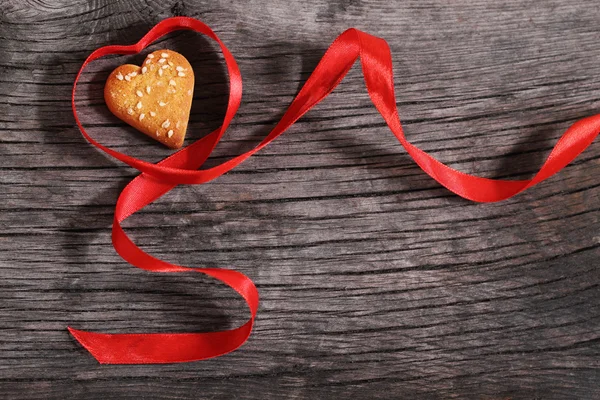 Одно печенье и красная лента в форме сердца — стоковое фото