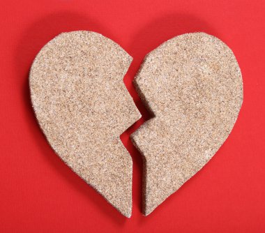 Broken heart from sand on the red background clipart