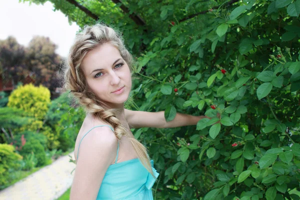 庭で青いドレスの若い魅力的なブロンドの女の子 — ストック写真