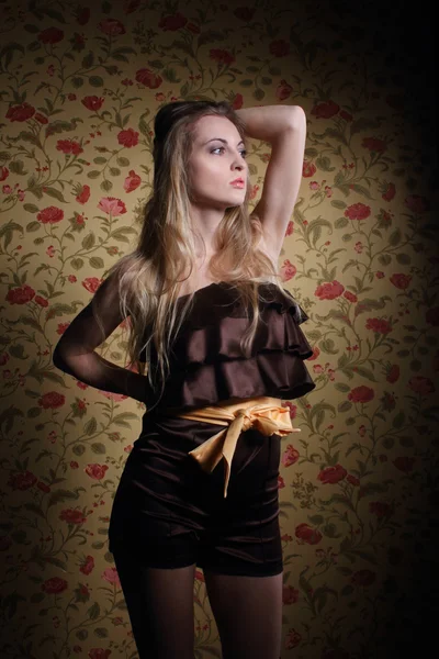 Vacker blond flicka i overaller nära väggen med rosor — Stockfoto