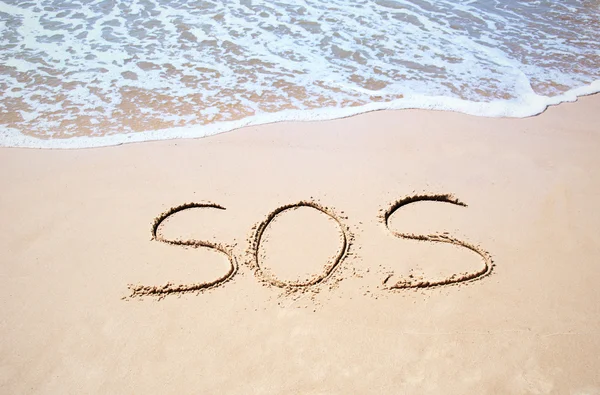 Inscripción "SOS" en la arena y la ola marina — Foto de Stock