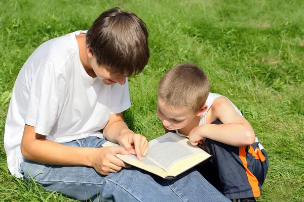 Teenager and kid with a book — Stock Photo, Image