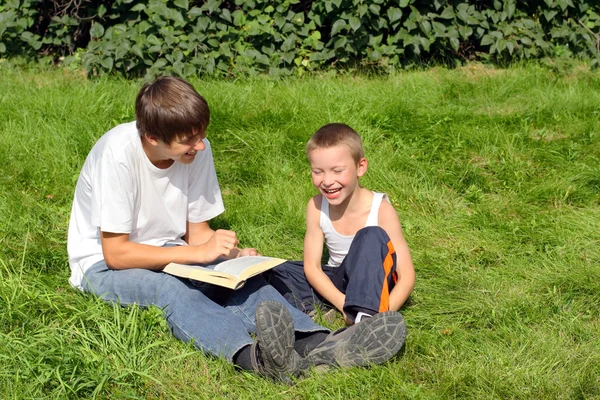 Adolescente e criança com um livro — Fotografia de Stock