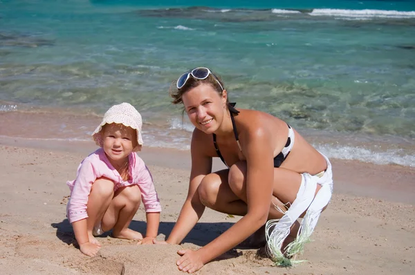 stock image Mother with the child playing with sand on beach