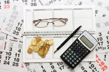 Sheets of a calendar with coins and a notebook clipart