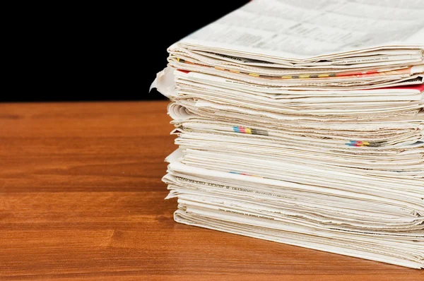 Heap of newspapers on a wooden table — Stock Photo, Image