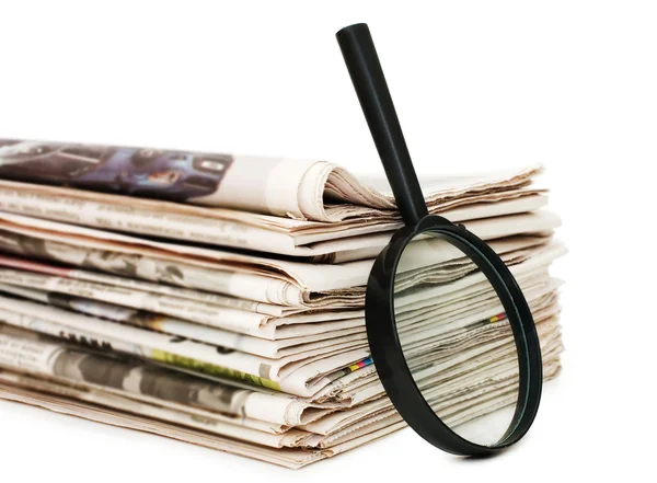 Magnify glass over a stack of newspaper — Stock Photo, Image