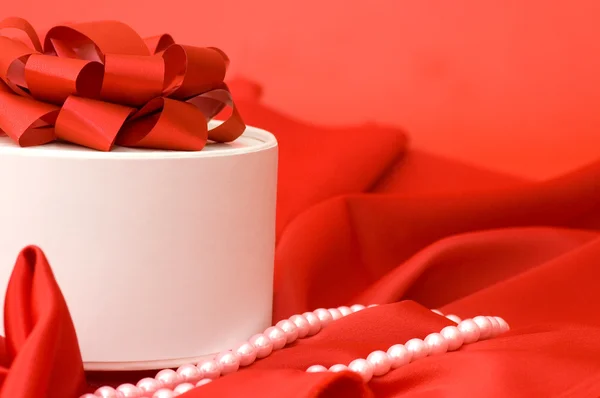 Scatola con un regalo su un tessuto rosso — Foto Stock