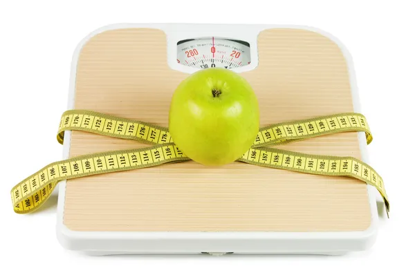 Масштаб, лента и яблоко на белом фоне — стоковое фото