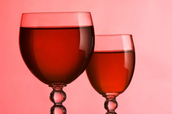 Wijnglazen met wijn op een roze achtergrond — Stockfoto