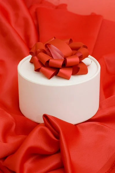 Boîte avec un cadeau sur un tissu rouge — Photo