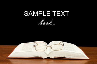 Eyeglasses on books on a wooden table clipart