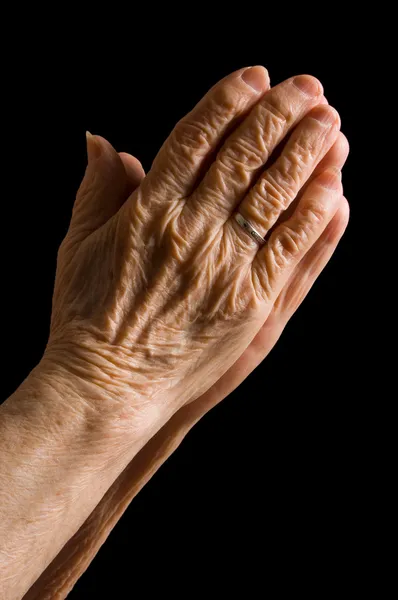 Händerna på den gamla kvinnan på en svart bakgrund — Stockfoto