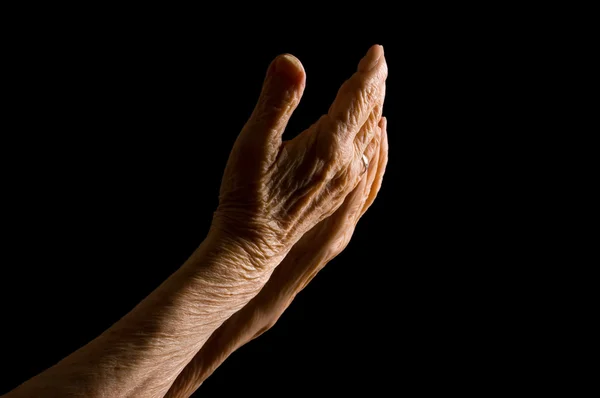 Las manos de la anciana sobre un fondo negro —  Fotos de Stock