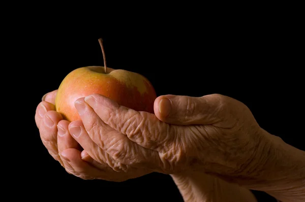 Jabłko w ręce staruszki na czarny — Zdjęcie stockowe
